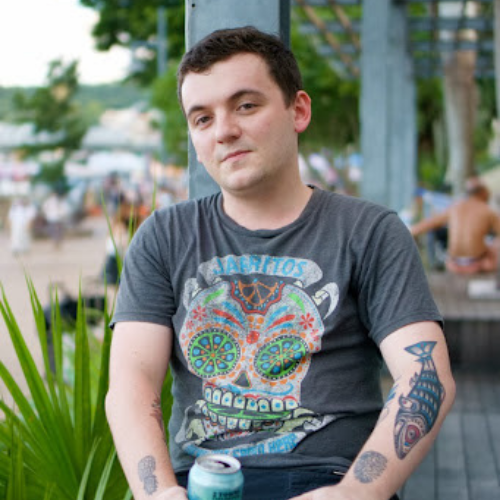 photo of graduate sitting outside of his restaurant